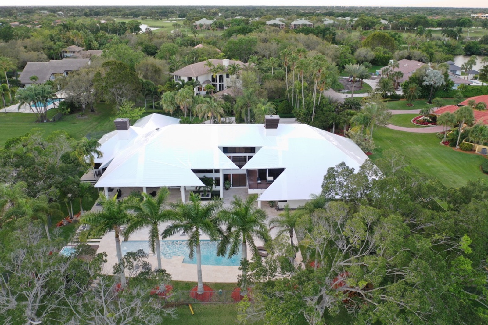 Custom estate home with a complex multi-plane roofline and pool, fully sealed under a white RoofWrap membrane