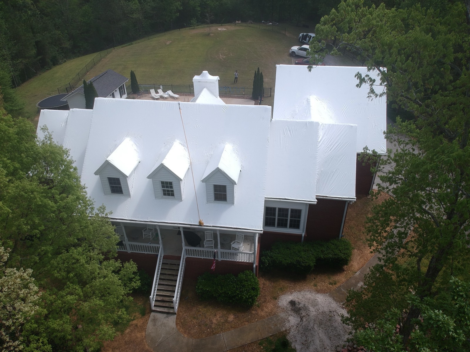 The same brick home sealed under a clean white RoofWrap membrane