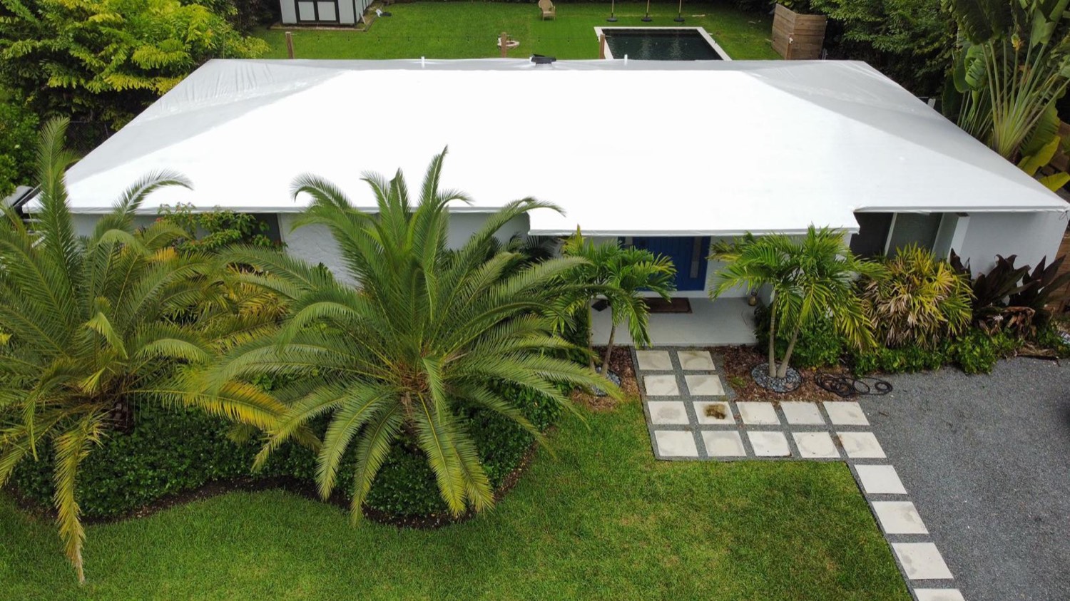 Modern home sealed under a white RoofWrap membrane after a storm
