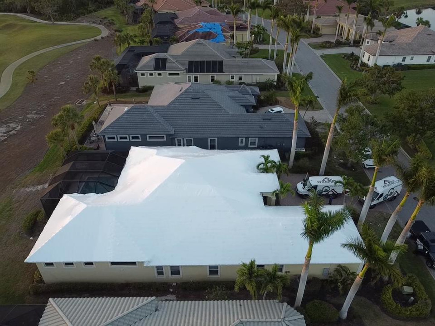 Suburban asphalt shingle home sealed under a clean white RoofWrap membrane after a storm